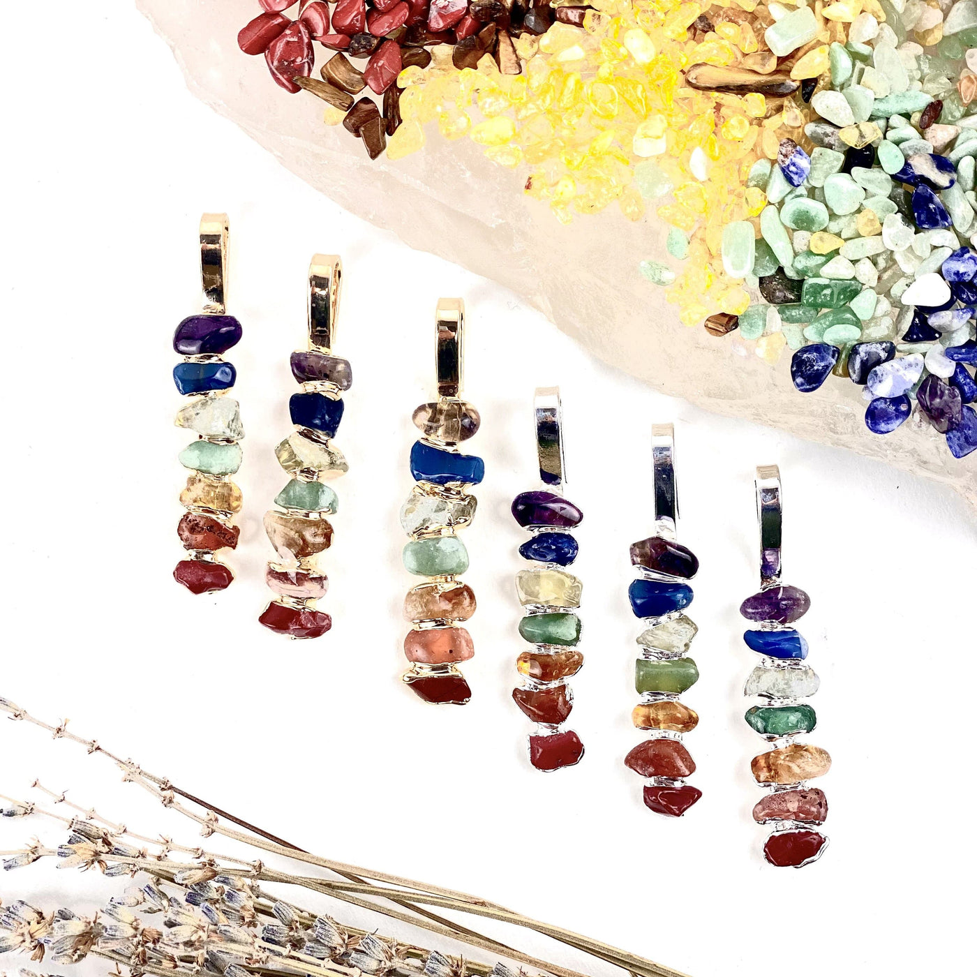 aligned tumbled stone chakra pendants in electroplated gold and silver displayed next to each other 