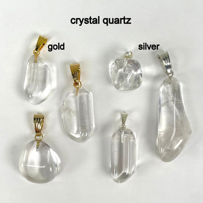close up of six tumbled crystal quartz pendants in gold and silver for details, finish comparison, and possible stone variations