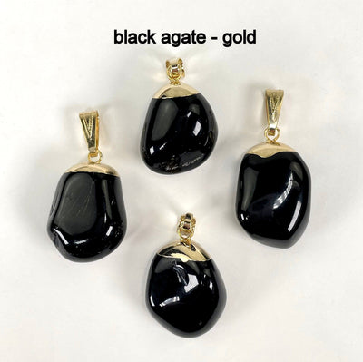 close up of four tumbled black agate pendants in gold for possible stone variations and details
