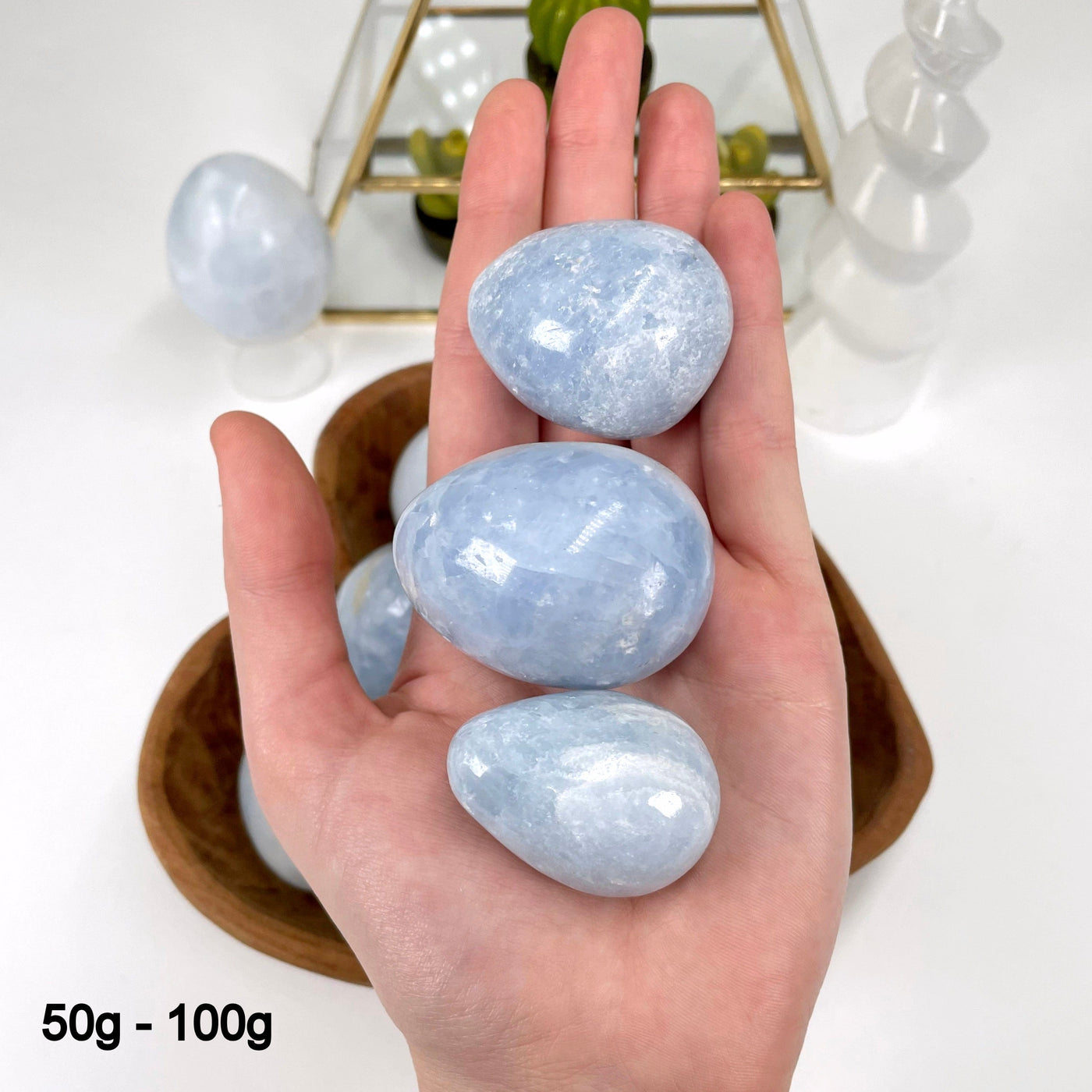 three 50g - 100g blue calcite polished eggs in hand for size reference and possible variations