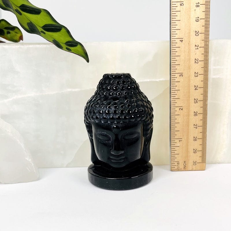 buddha head next to a ruler for size reference 
