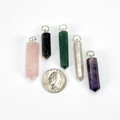 close up of the gemstone pendants displayed next to a quarter for size reference 