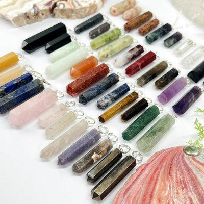 multiple gemstone pendants with with silver toned bails displayed showing the differences in the stone colors and sizes 