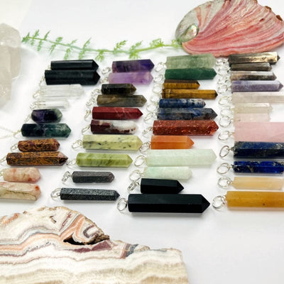 multiple gemstone pendants with with silver toned bails displayed showing the differences in the stone colors and sizes
