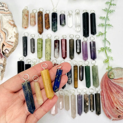 multiple gemstone pendants with circle silver bail displayed showing the different stone options available. gemstones in hand for size reference 