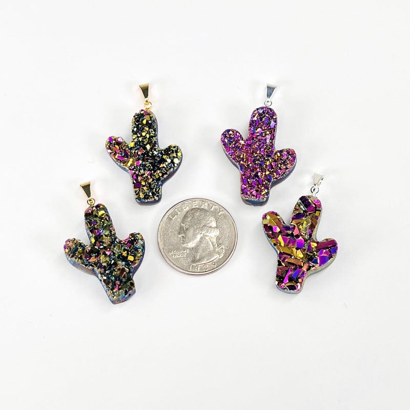 multiple cactus pendants with a rainbow titanium finish next to a quarter for size reference 
