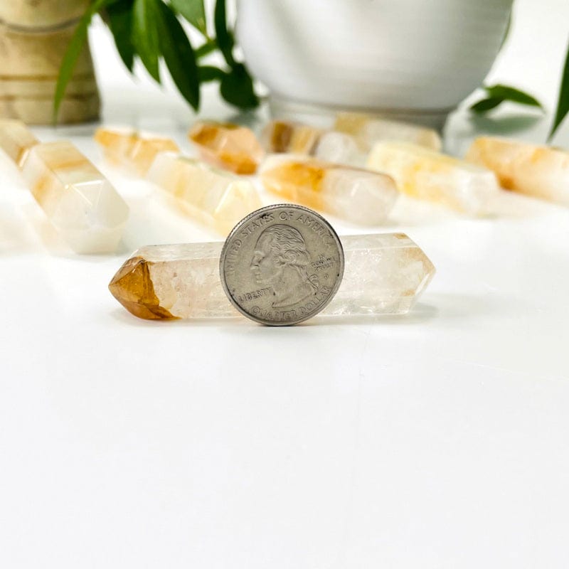 golden healer quartz double terminated point in front of quarter for size reference