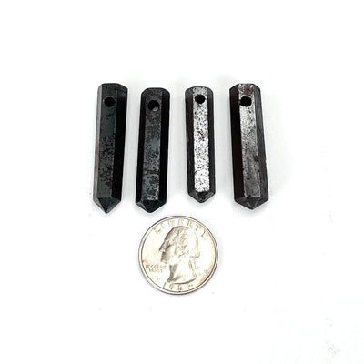 hematite drilled beads next to a quarter for size reference 