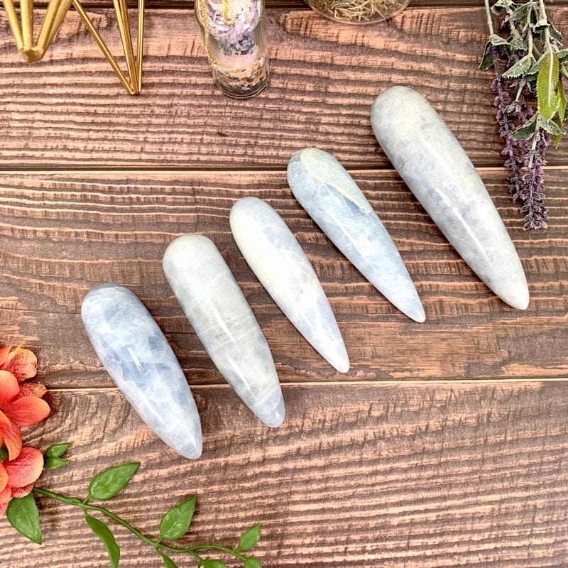 5 blue calcite massage wands laid on a wood panel