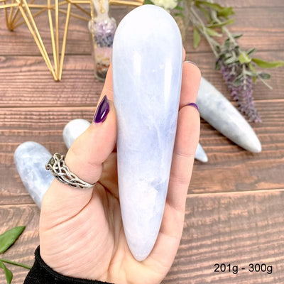 201 gram - 300 gram blue calcite wand in hand with wood background