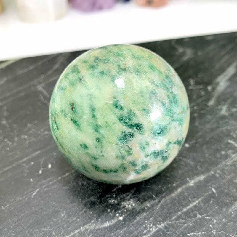 close up of one fuchsite sphere on black marble background