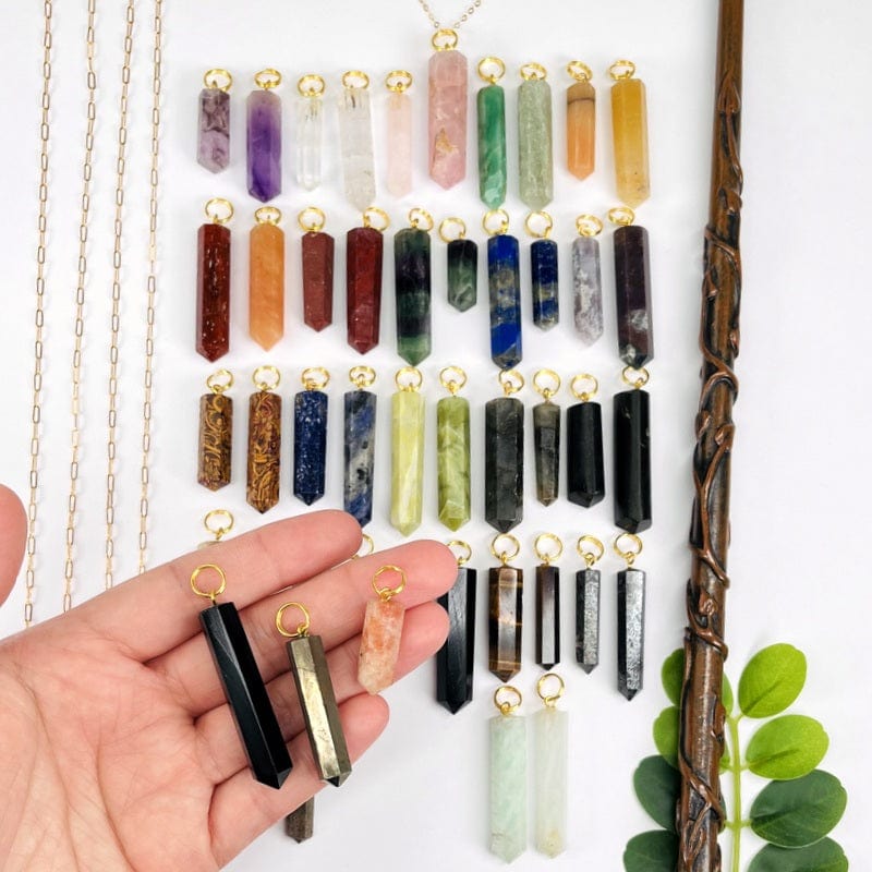multiple gemstone pendants in hand for size reference 