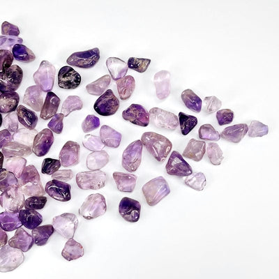 Assorted amethyst tumbled stones on a white background.