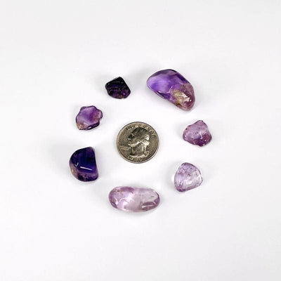 Amethyst tumbled stones assorted sizes as included in this package next to a quarter for comparision.
