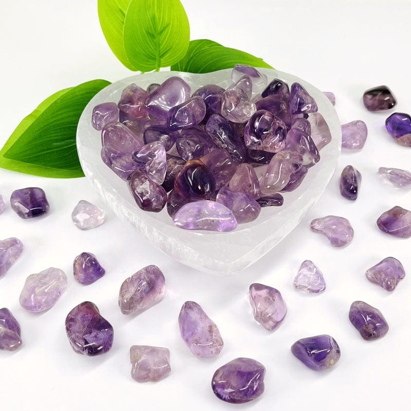 Amethyst tumbled stones in a selenite bowl with more in the background