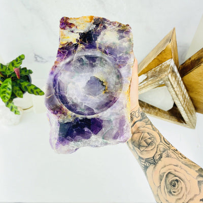 Hand holding Rainbow Flourite Display Bowl up with various decorations in the background