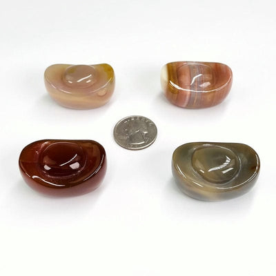 yuanbao shaped carved carnelian stones next to a quarter for size reference 