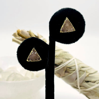 close up of one pair of gold natural druzy triangle stud earrings on display