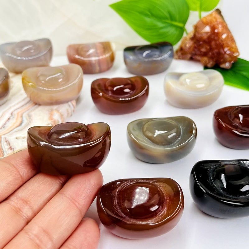 yuanbao shaped carved carnelian stones displayed to show the differences in the color patterns 