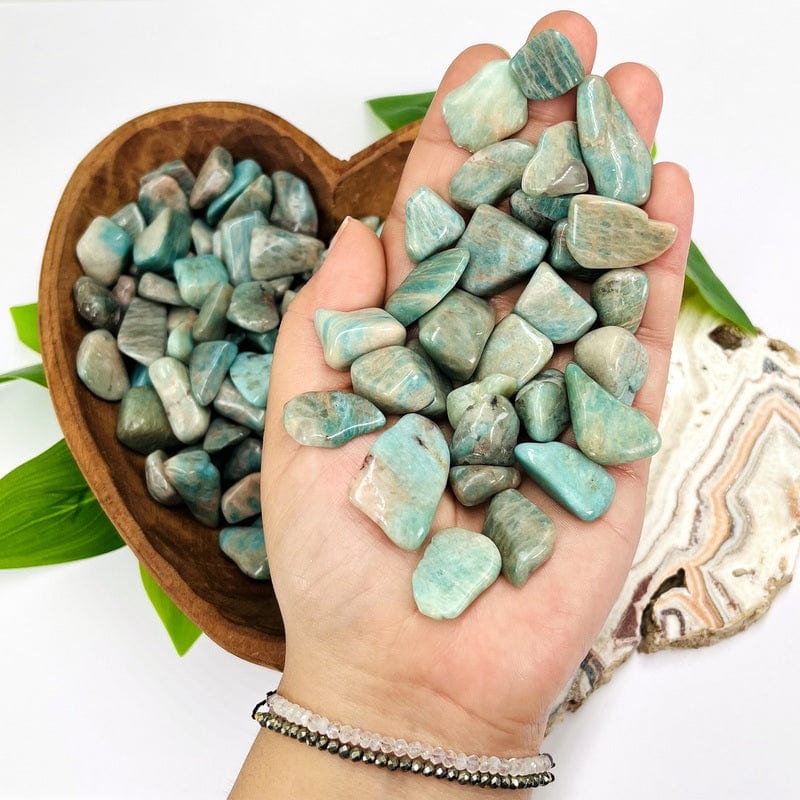 amazonite tumbled stones in hand for size reference  