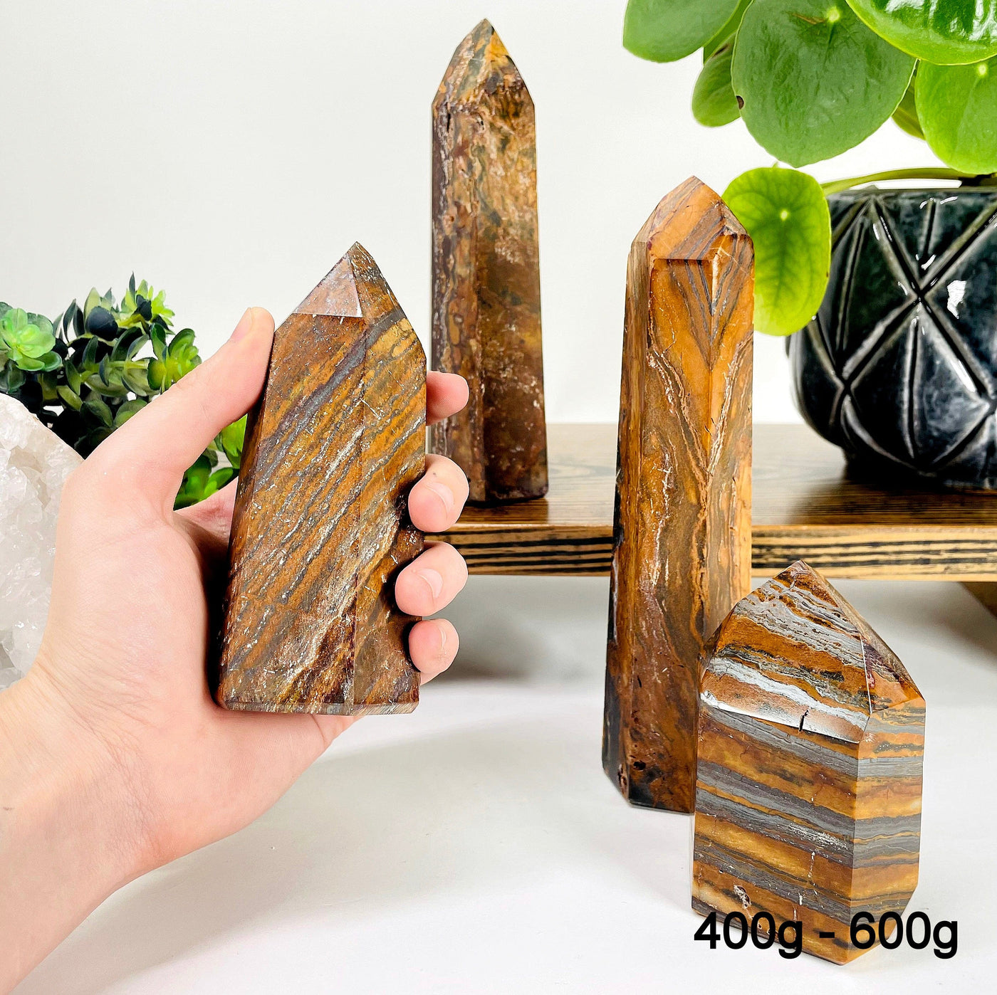 four 400g - 600g tiger eye polished points on display for possible variations with one in hand for size reference