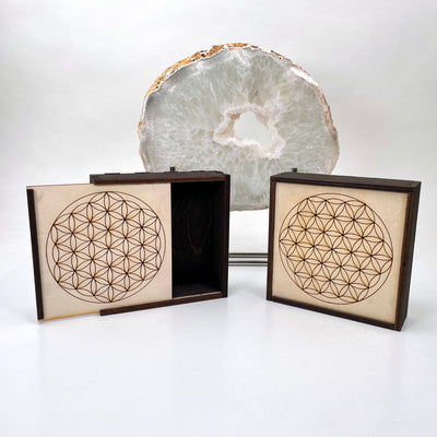 two flower of life wooden storage boxes in front of backdrop; one box half opened 