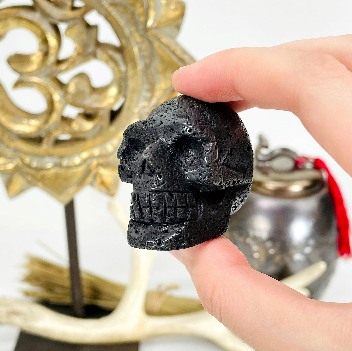 close up of one lava skull head in hand in front of backdrop for size reference and details
