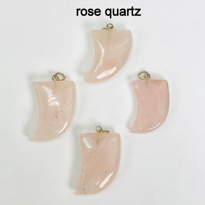 close up of four tumbled rose quartz horn pendants on white background for details and possible variations
