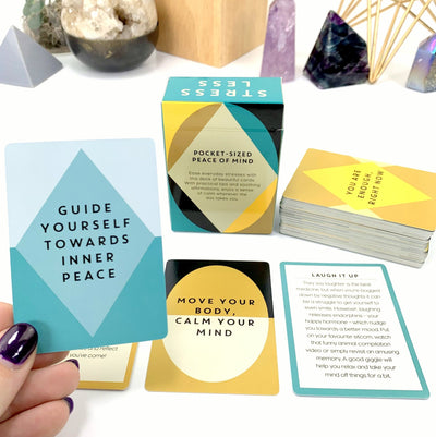 A AFFIRMATION CARD IN HAND WITH THE CASING AND CARDS LAID OUT ON A WHITE BACKGROUND