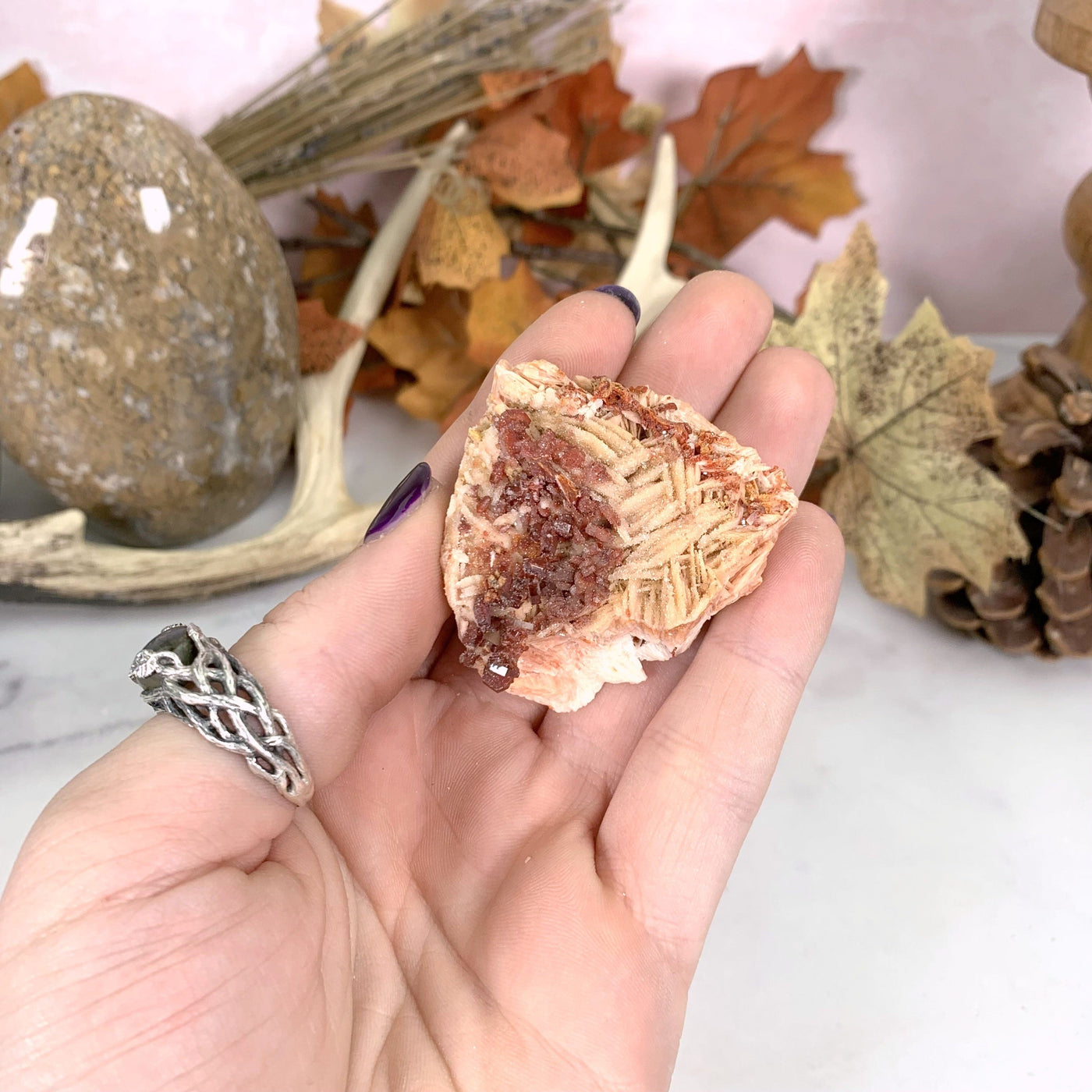 top view of vanadinite cluster in hand with white marble background