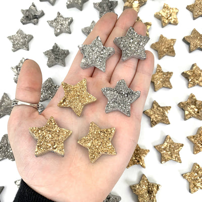 3 gold and 3 silver titanium stars in a woman's palm with more stars on a white background