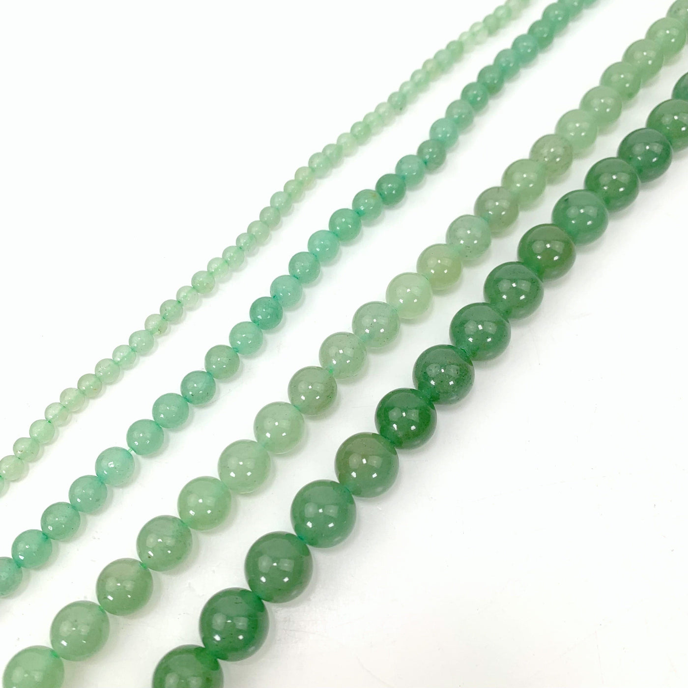 all 4 variations of green aventurine on a white background from left to right smallest to biggest