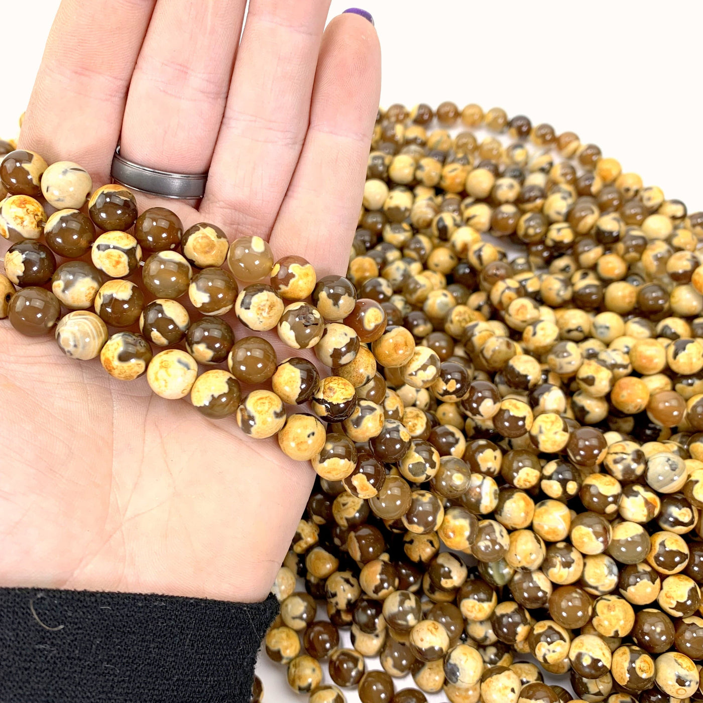 dyed yellow agates in hand with more beads in background