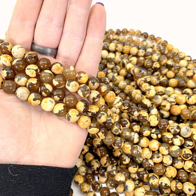 dyed yellow agates in hand with more beads in background