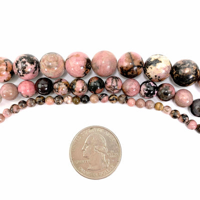 all 3 variations of rhodonite on a white background next to a quarter