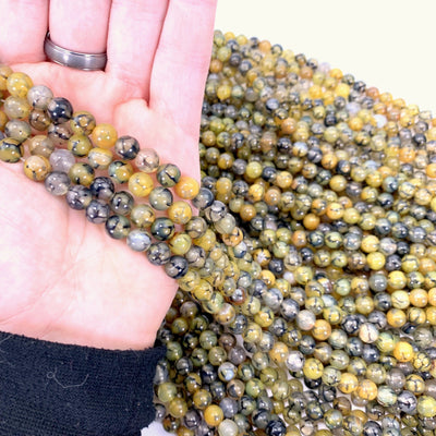 yellow agate beads in hand with more agate beads in the background