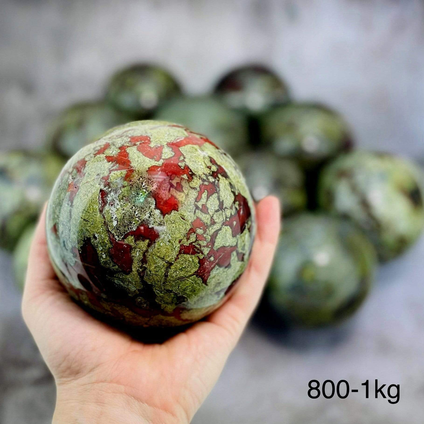 Dragon Blood Stone Spheres in Hand on Gray Background.