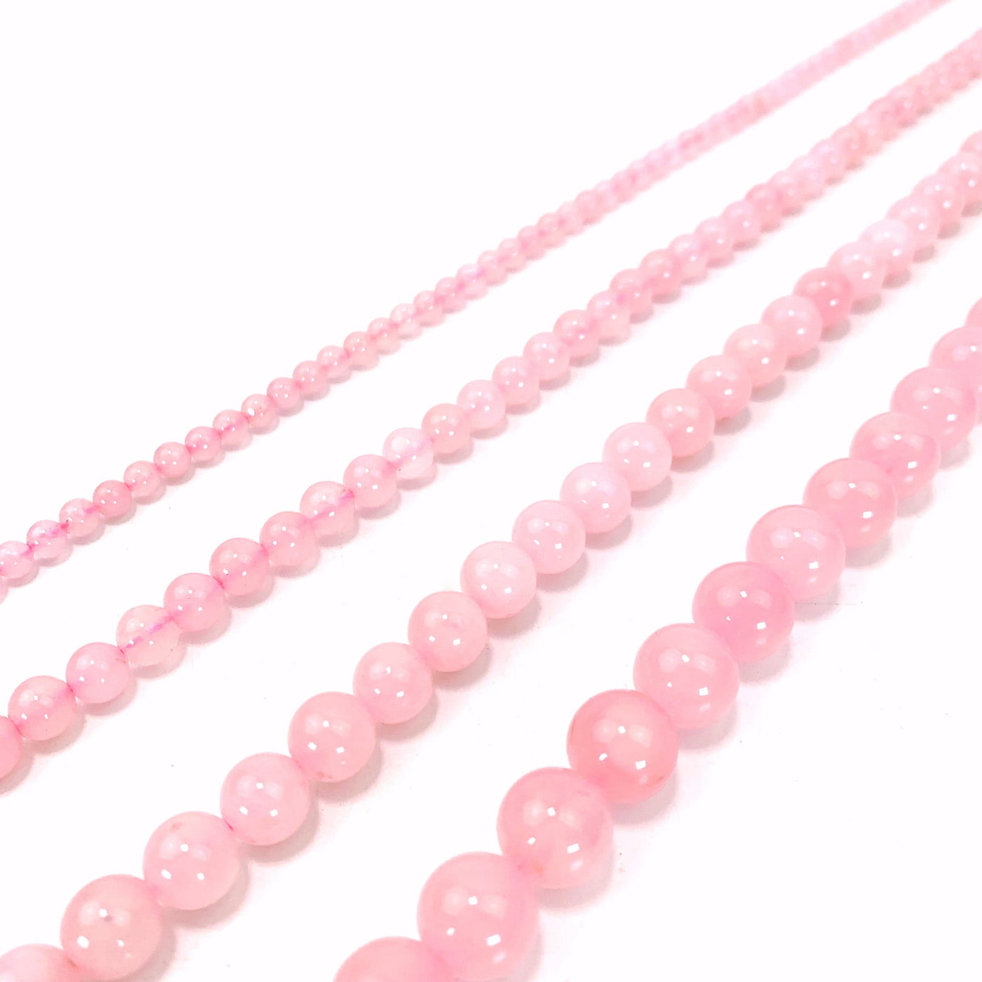 photo of four sizes of rose quartz beads on a white background