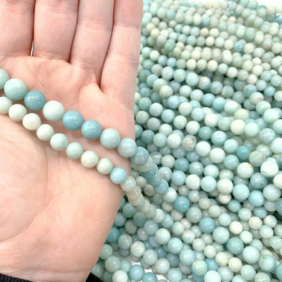 both variations of amazonite in hand with more amazonite beads in the background