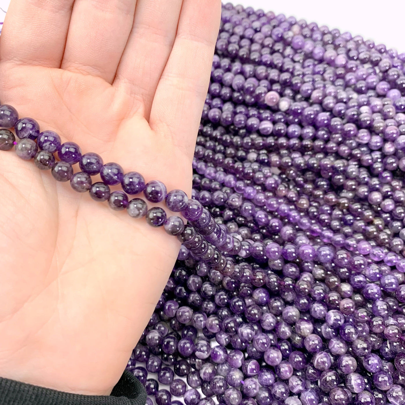 both sizing variations in hand with more amethyst beads in background