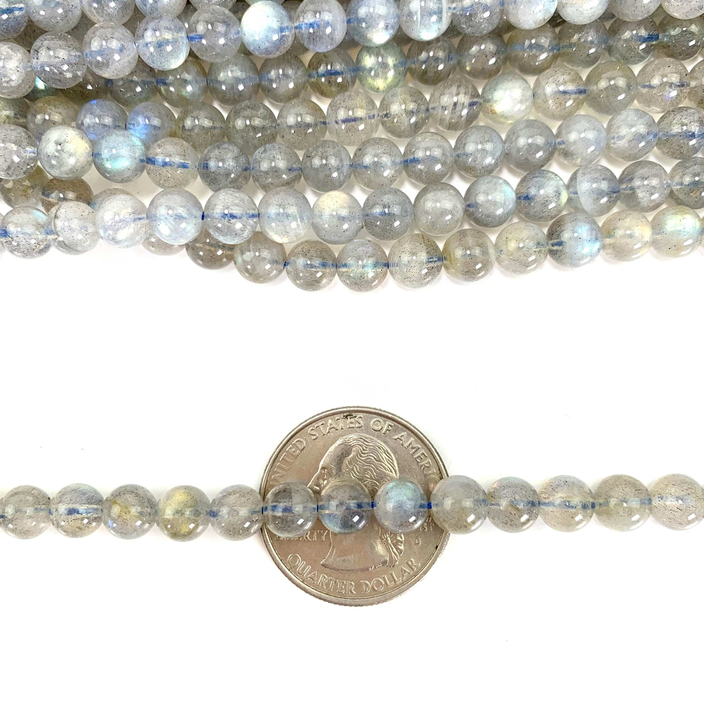 labradorite beads on a white  background with one strand over a quarter