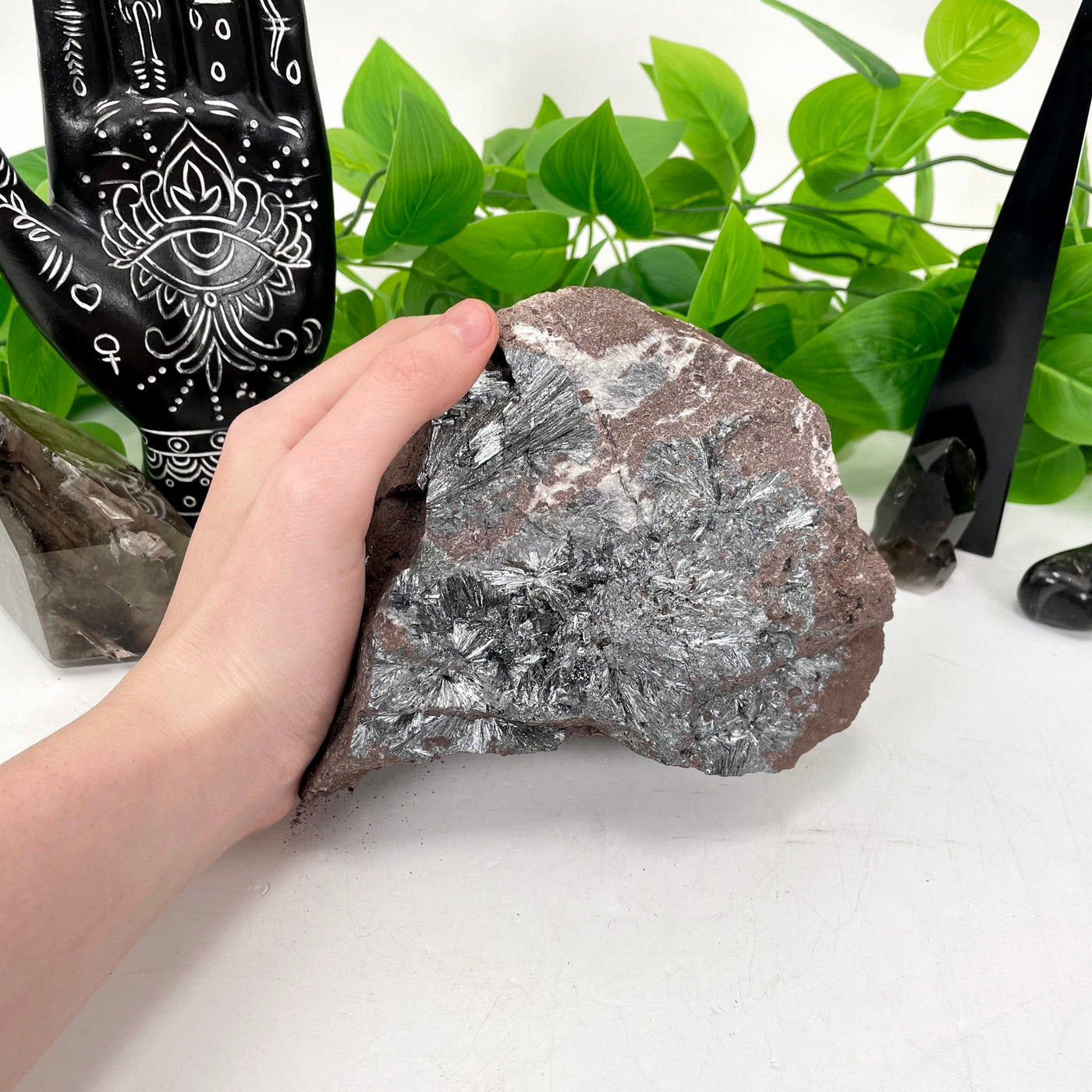 raw stibnite on matrix in hand for size reference