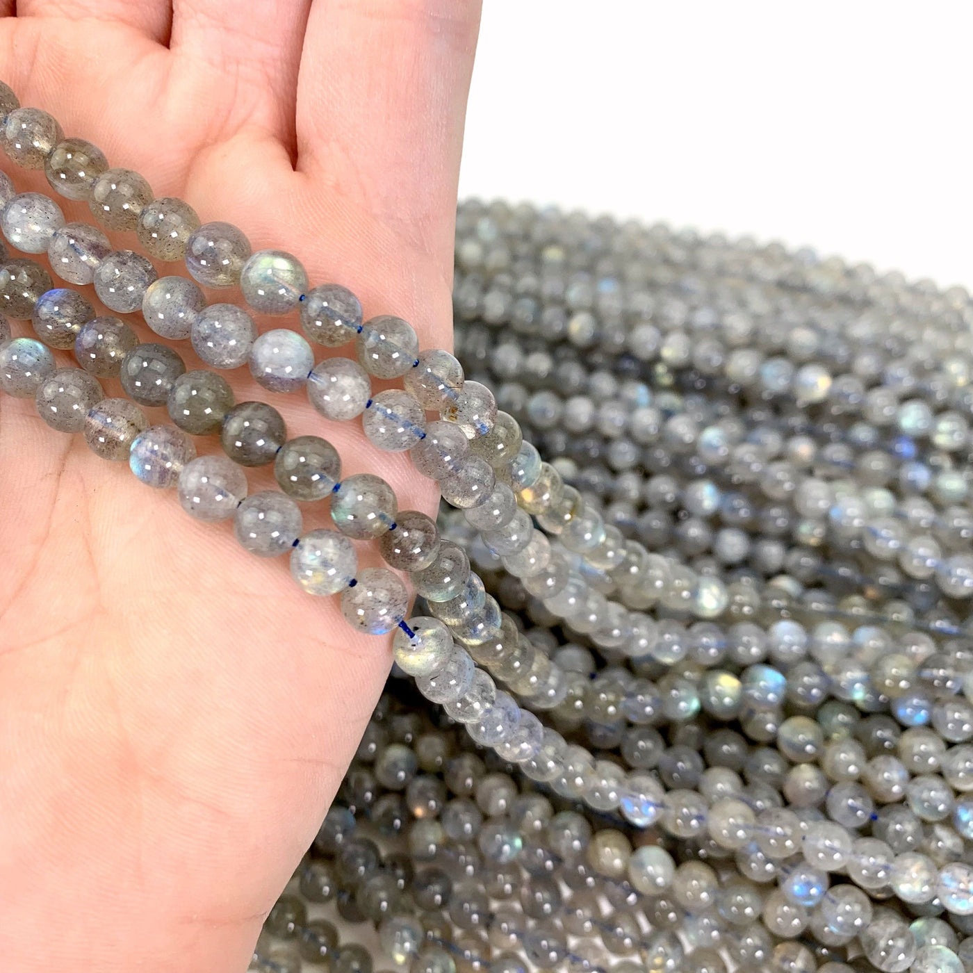 labradorite beads in hand with more labradorite beads in background