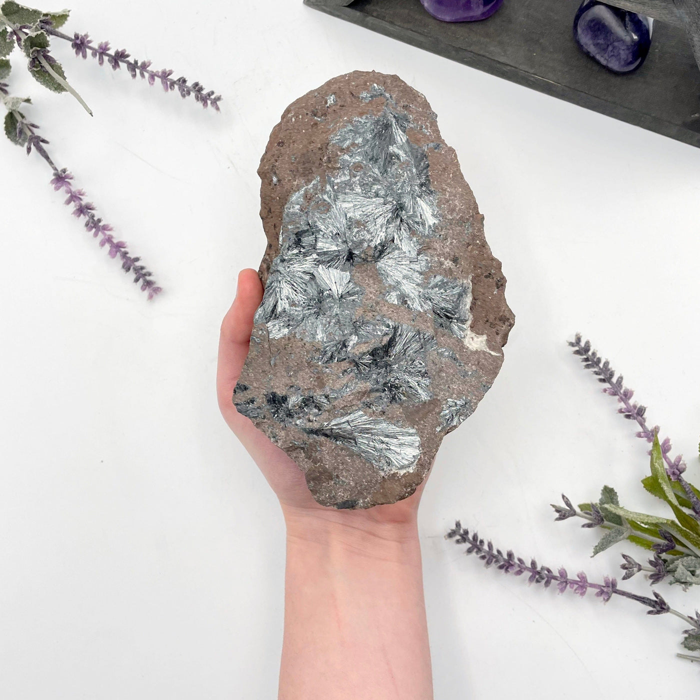 raw stibnite on matrix in hand for size reference