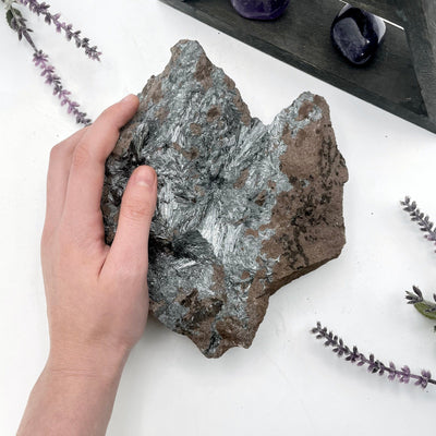 raw stibnite on matrix in hand for size reference