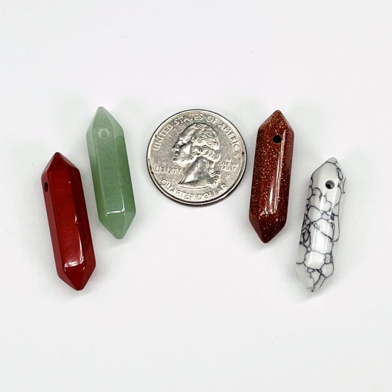 close up of the double terminated pencil point beads next to a quarter for size reference 