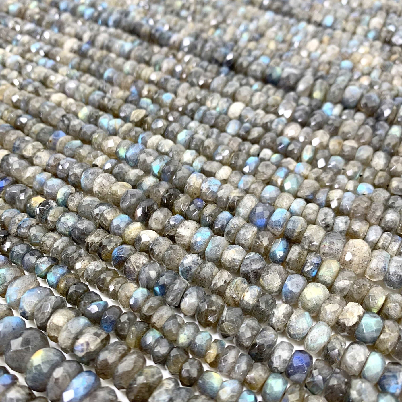 FACETED ROUND LABRADORITE BEADS LAID OUT ON A WHITE SURFACE