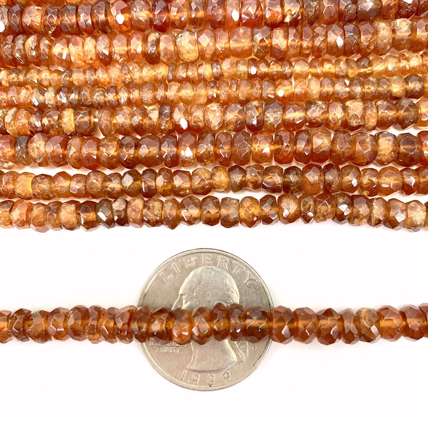 hessonite beads over a quarter with a white background