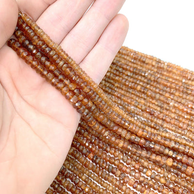 hessonite beads in hand wiith a white background