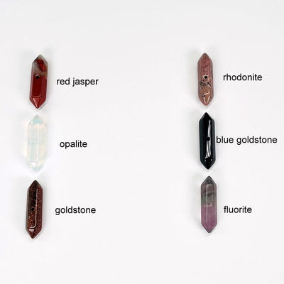 double terminated pencil point beads with a center drill hole next to their stone name. available in red jasper, opalite, goldstone, rhodonite, blue goldstone, and fluorite 